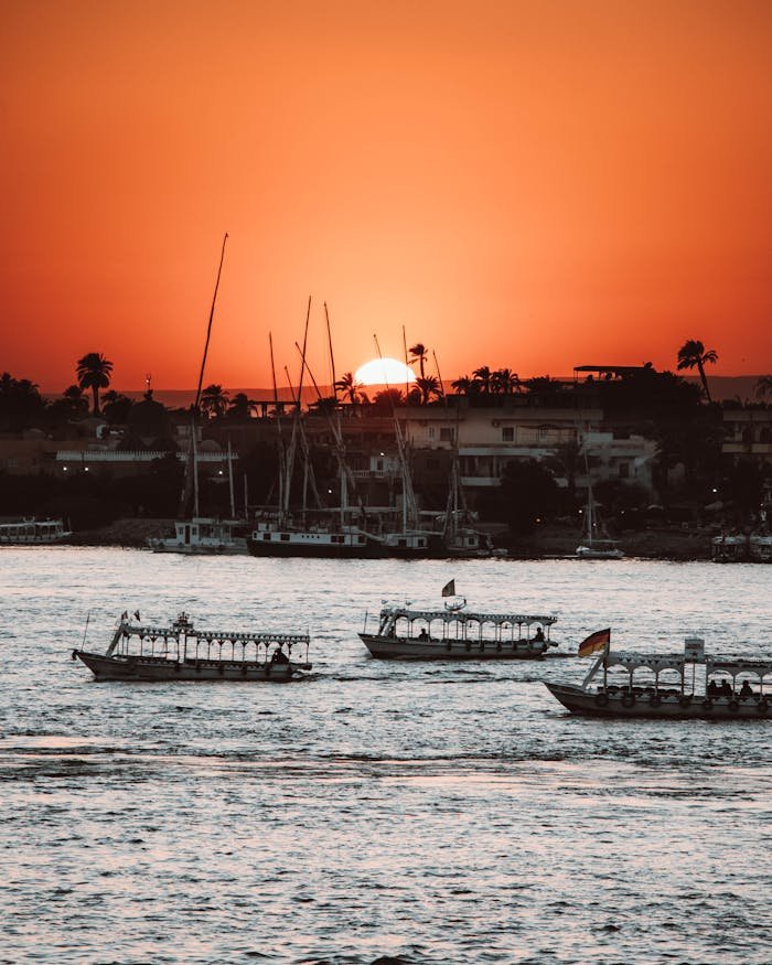 Serene sunset view of boats sailing on the Nile River in Luxor, Egypt.
