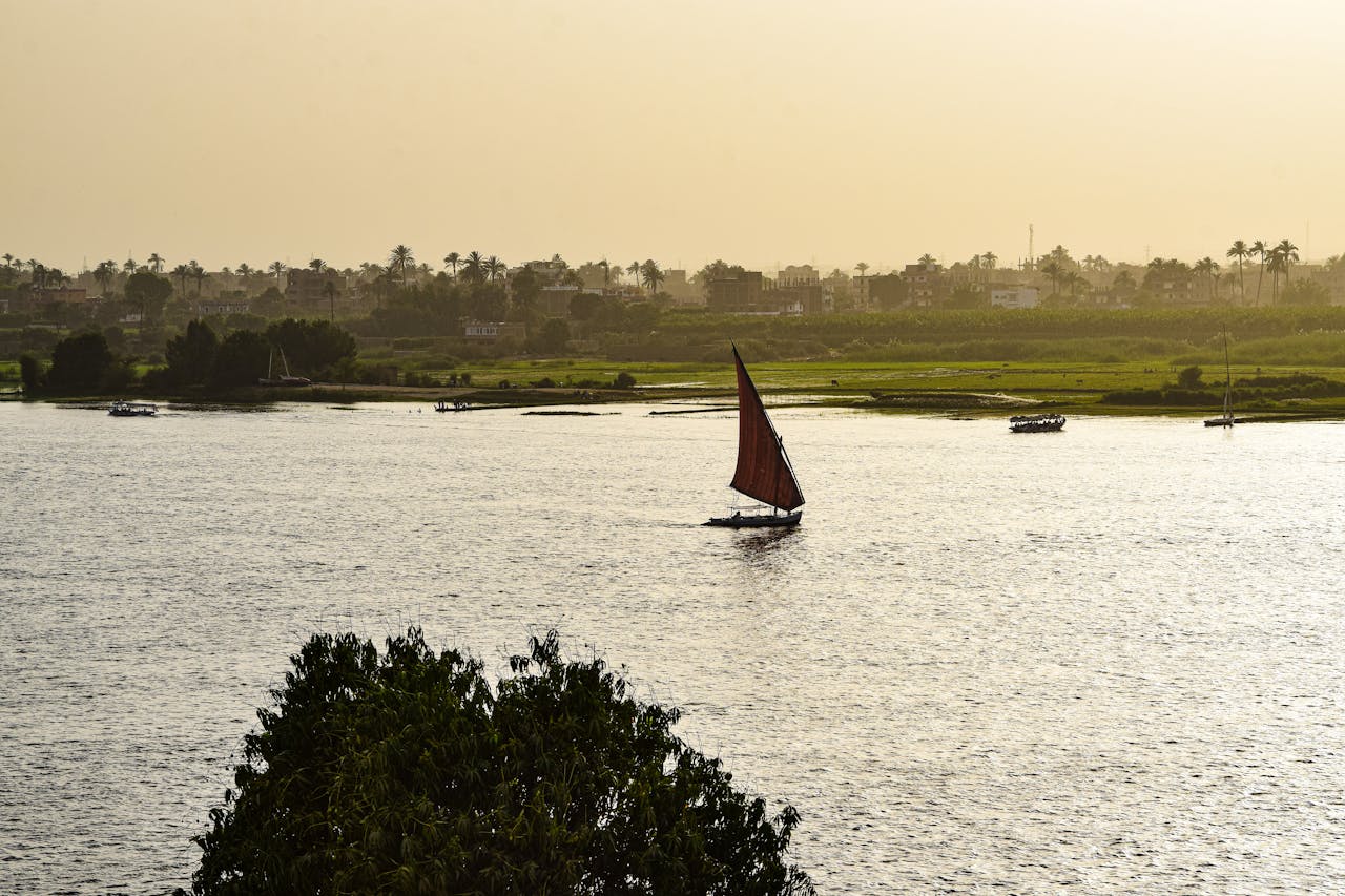 A traditional sailboat glides on the Nile River in Luxor, Egypt, as the sun sets.