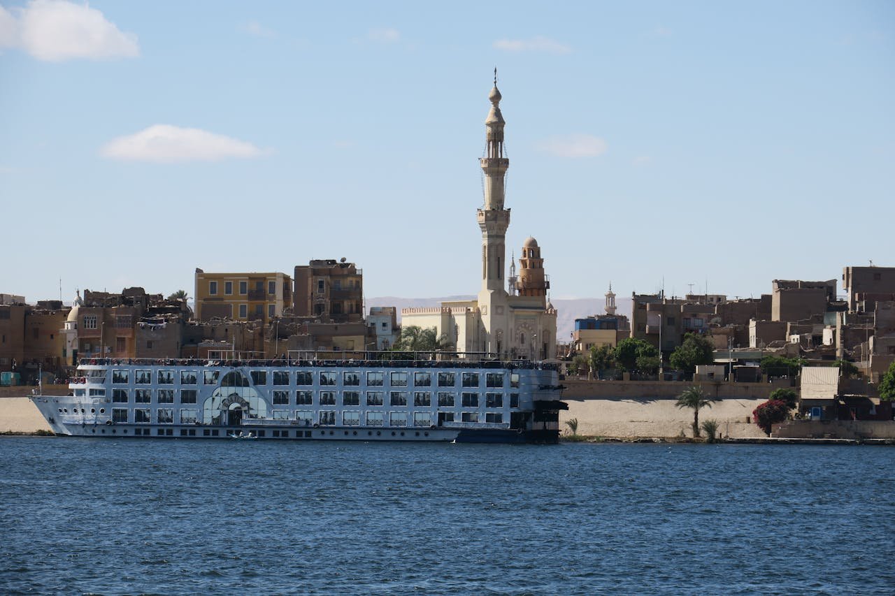 A cruise ship sails on the Nile River near a mosque in Aswan, Egypt.