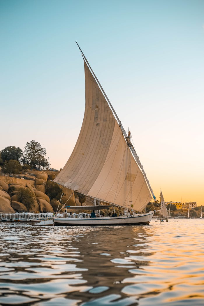 Home Scenic view of a traditional Egyptian felucca sailing at sunset on the Nile.