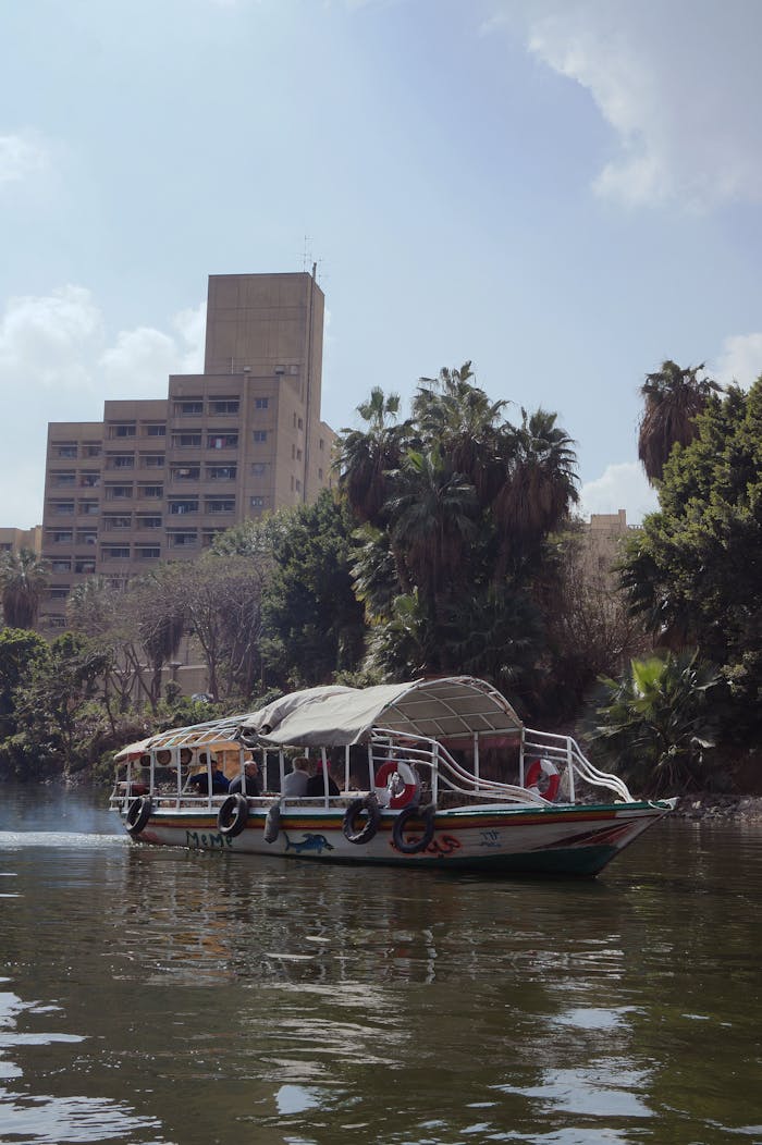 A traditional boat cruising along the Nile River in Cairo, surrounded by urban and natural landscapes.
